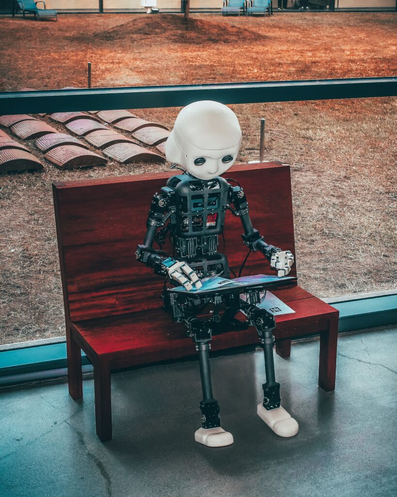 Robot sitting on a bench and browsing a tablet.